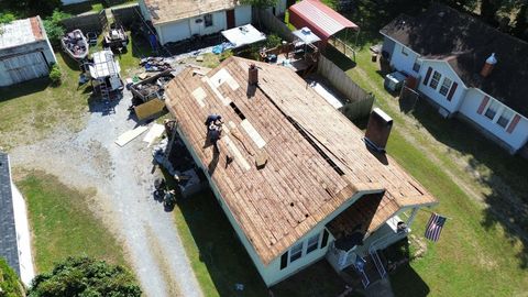 Aerial view of roofing contractors repairing exposed wood roof decking on a home