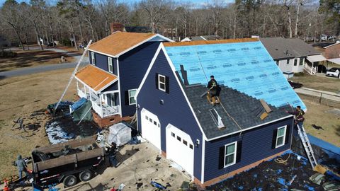 Roofing crew replacing an asphalt shingle roof over protective blue underlayment