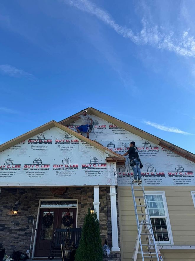 Exterior crew installing house wrap and siding on the gable of a residential home