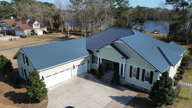 Aerial view of a coastal home with a standing seam metal roof and finished gutter system