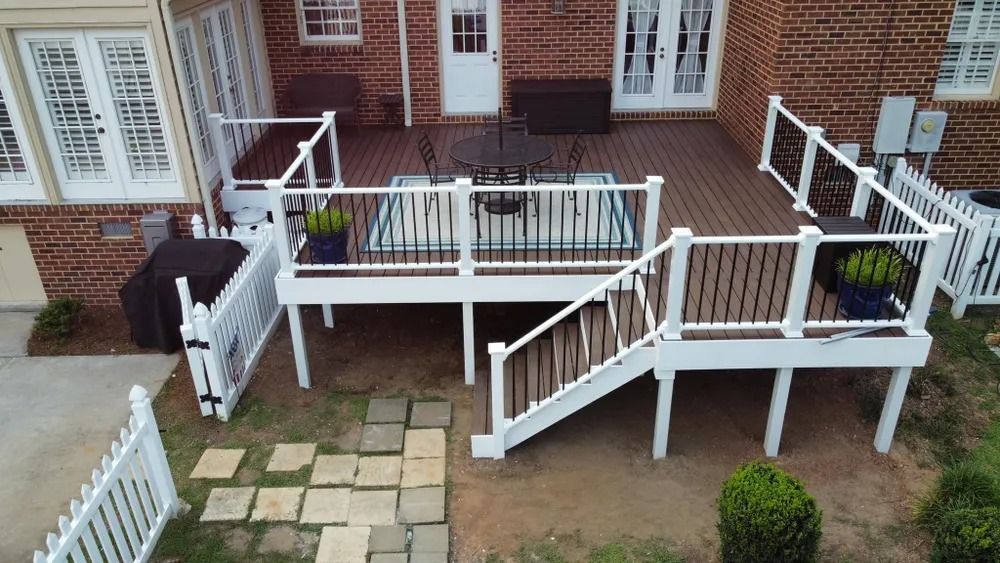 White accessibility ramp and steps attached to a brick building with a small patio and garden path.