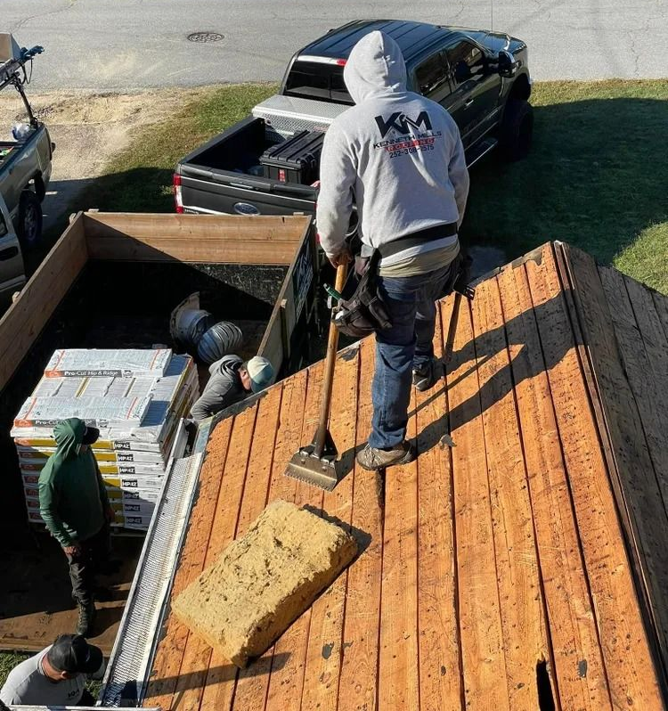 Aerial view of roofing contractors repairing exposed wood roof decking on a home