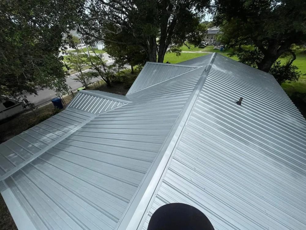 Silver metal roof with ridges and trees surrounding the house from above
