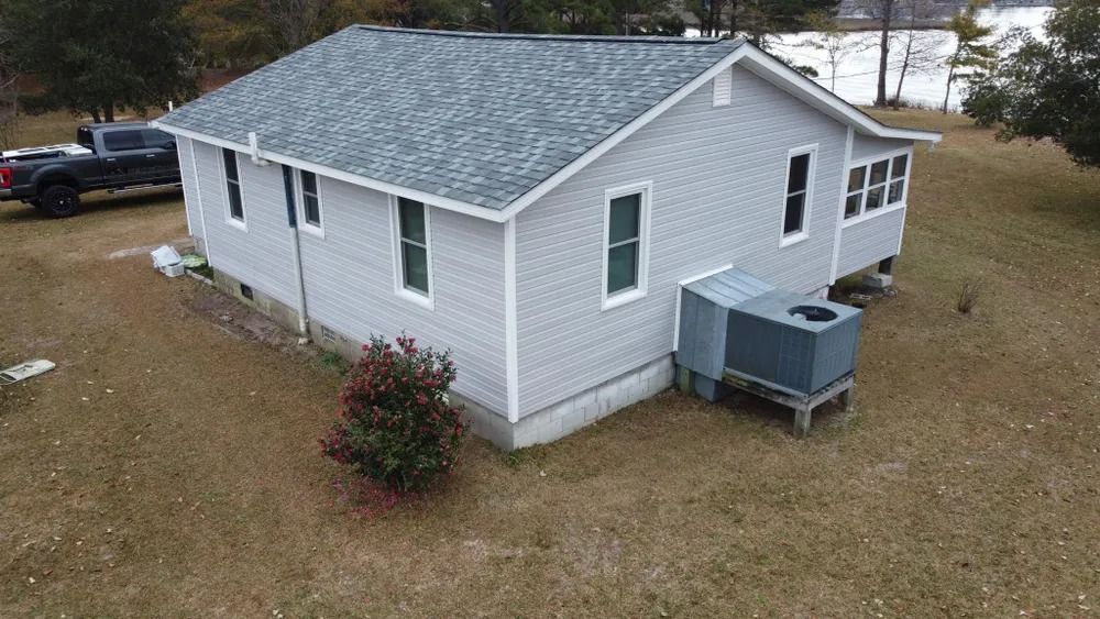 Gray single-story house with white trim and a small fenced yard, viewed from above.