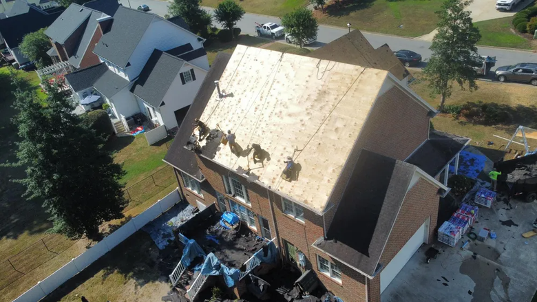 Aerial view of a house with a partially covered roof during roof repair or replacement.