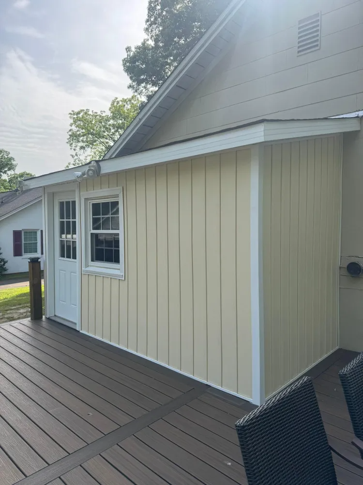 House exterior with cream siding and a white door beside a brown wooden deck
