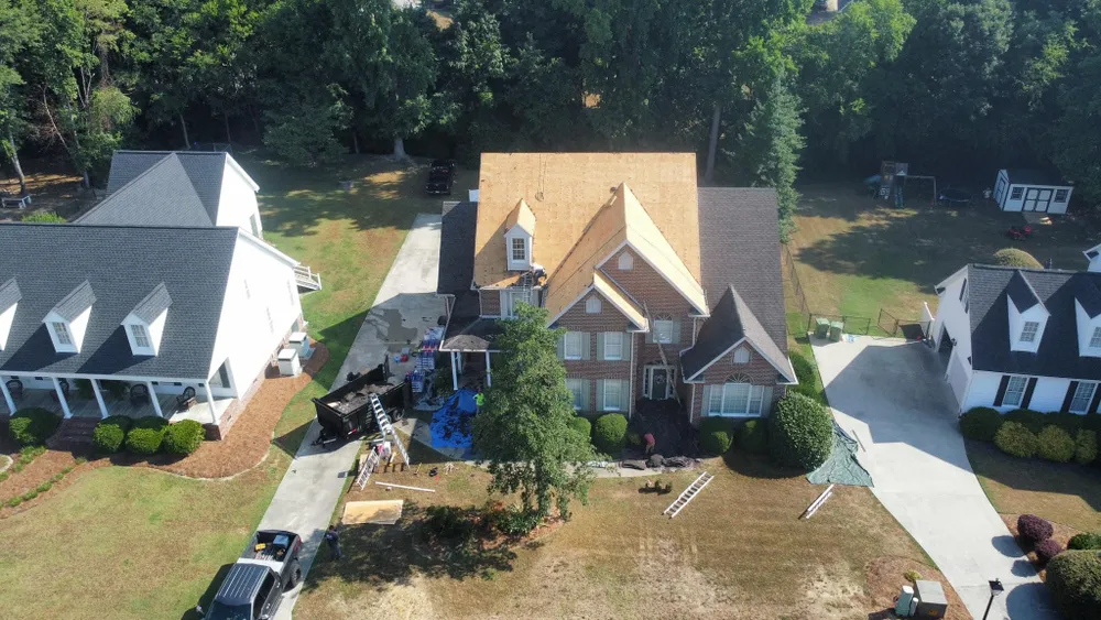 Aerial view of three suburban houses with lawns, driveways, and trees