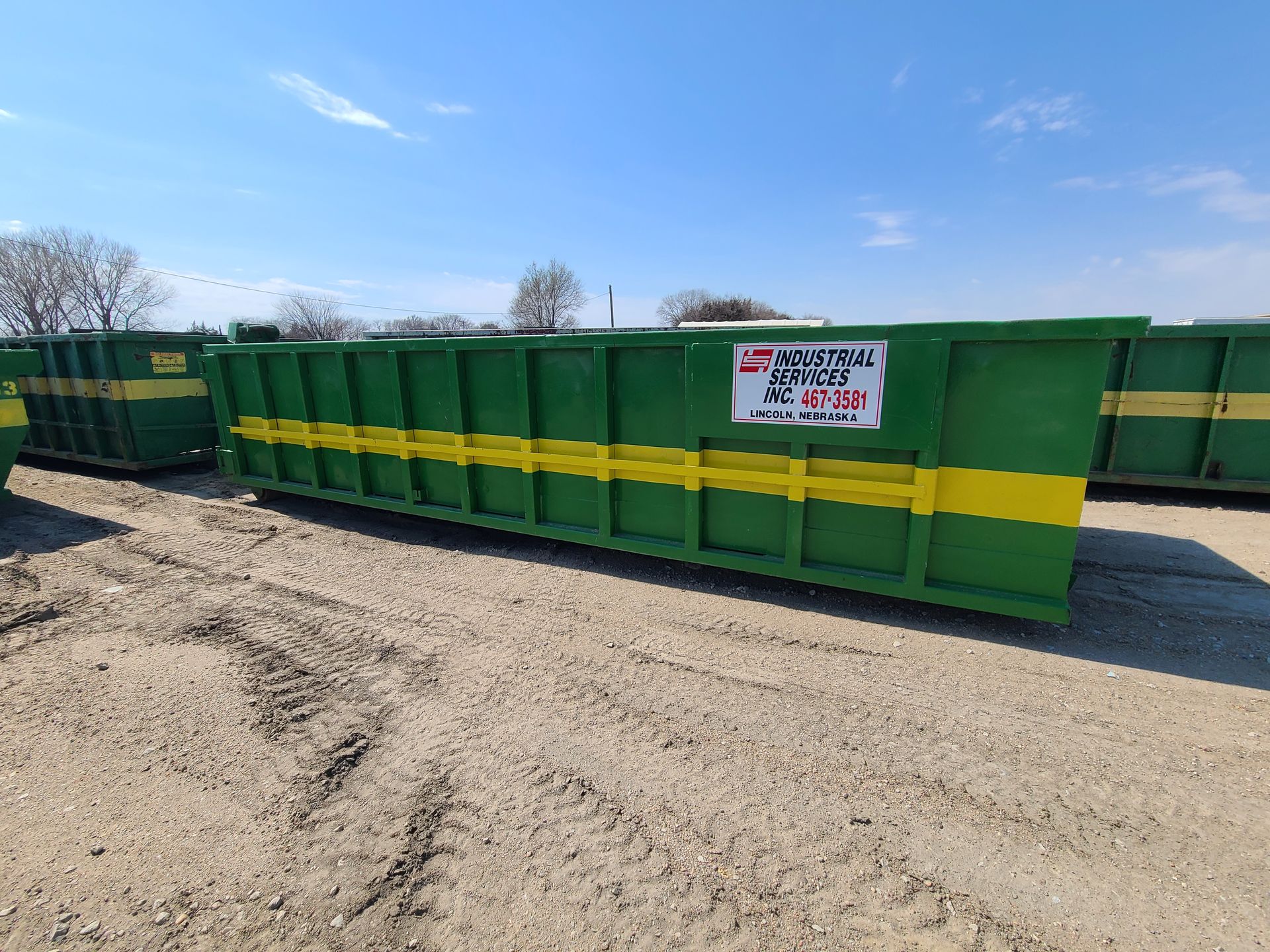 Beige roll-off dumpster with a black lid on a white background, ideal for waste disposal. Roll-off d