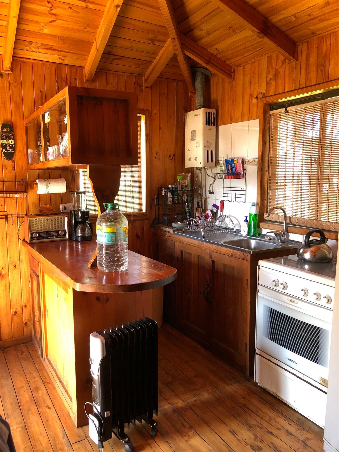 Cocina tipo cabaña de madera con encimeras, estufa, fregadero y calentador de aceite.