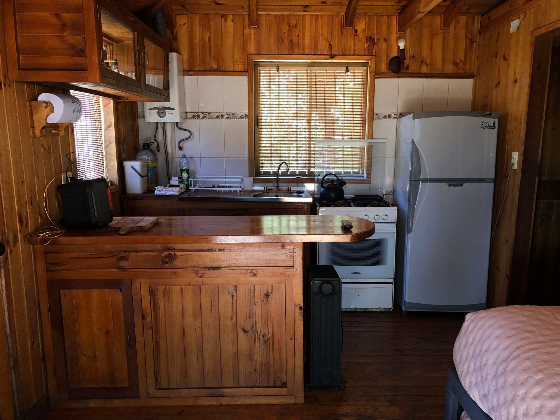 Acogedora cocina estilo cabaña con paneles de madera, encimeras, estufa y refrigerador. 