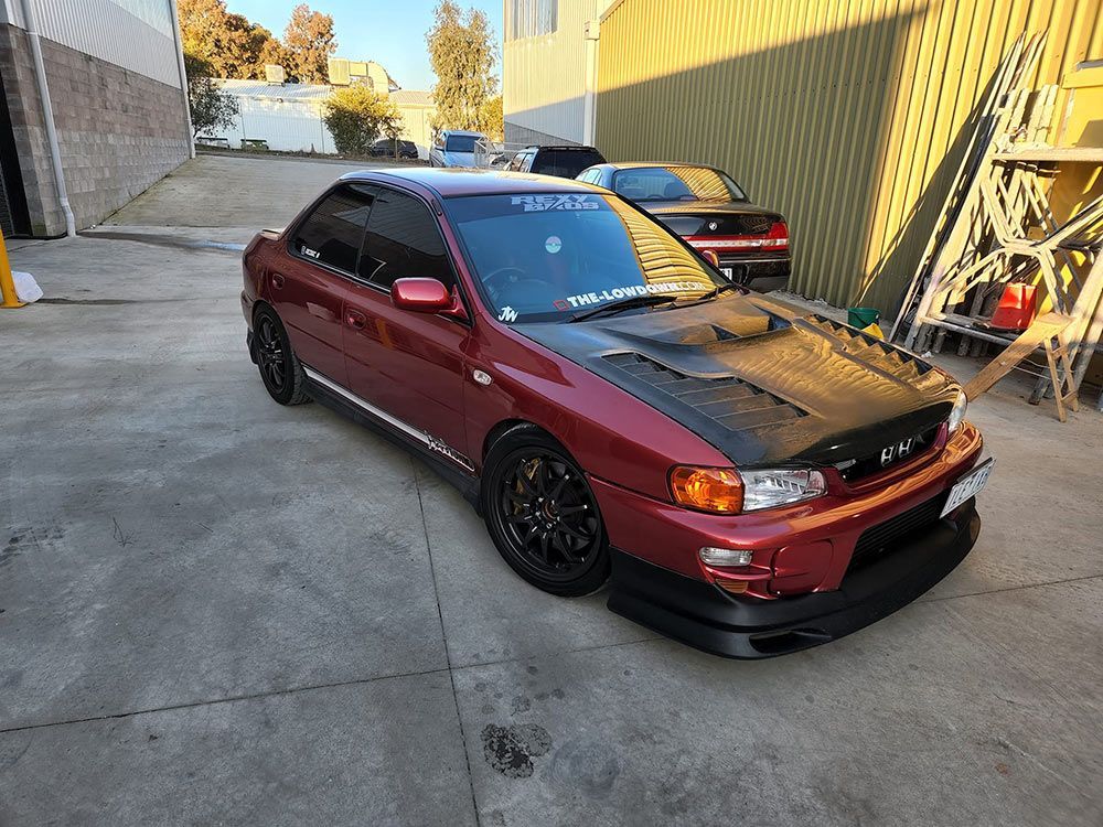 A Red Car with A Black Hood Is Parked in A Parking Lot — Genesis Automotive Services in Lavington, NSW
