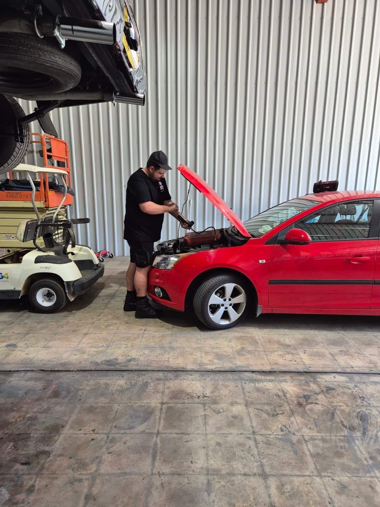 A Man is Working on a Red Car in a Garage — Genesis Automotive Services In Lavington, NSW