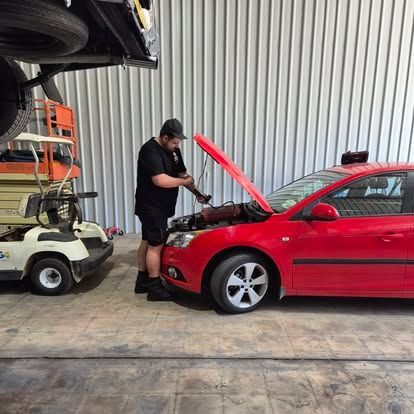 Mechanic working on a red car with the hood open in a garage.— Genesis Automotive Services in Lavington, NSW