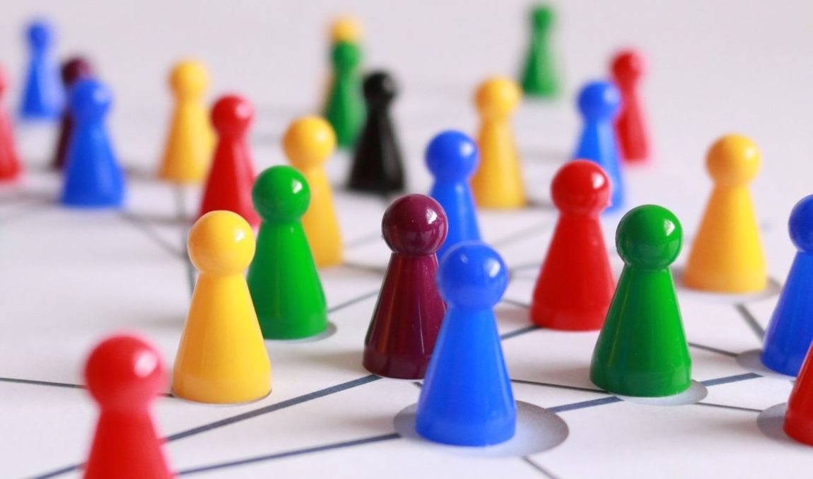 Kleurrijke plastic pionnen, verbonden door lijnen op een bord, suggereren strategie of netwerken.