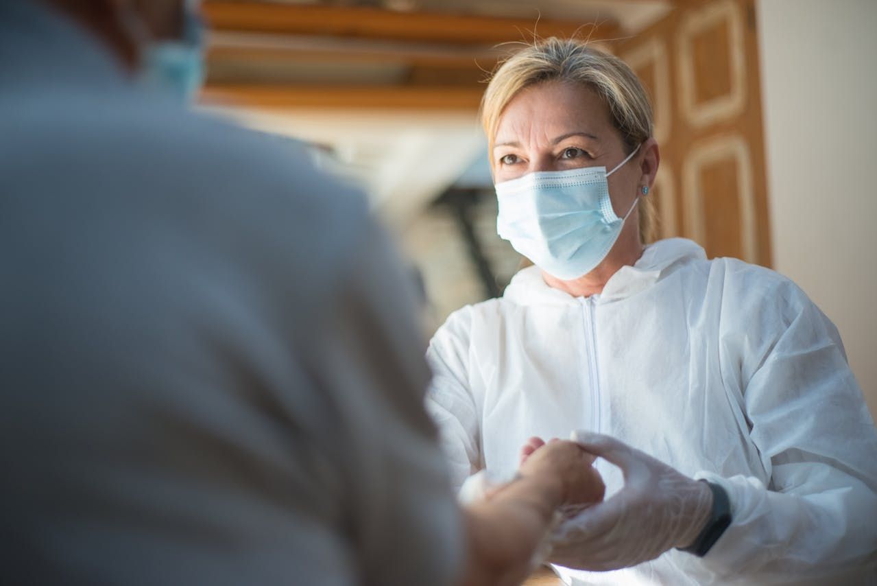 Healthcare worker in mask and gloves shaking hands with a patient in a clinic
