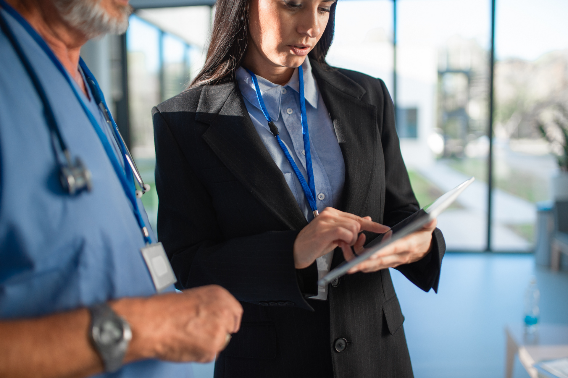 a woman holding a tablet explaining something to a doctor
