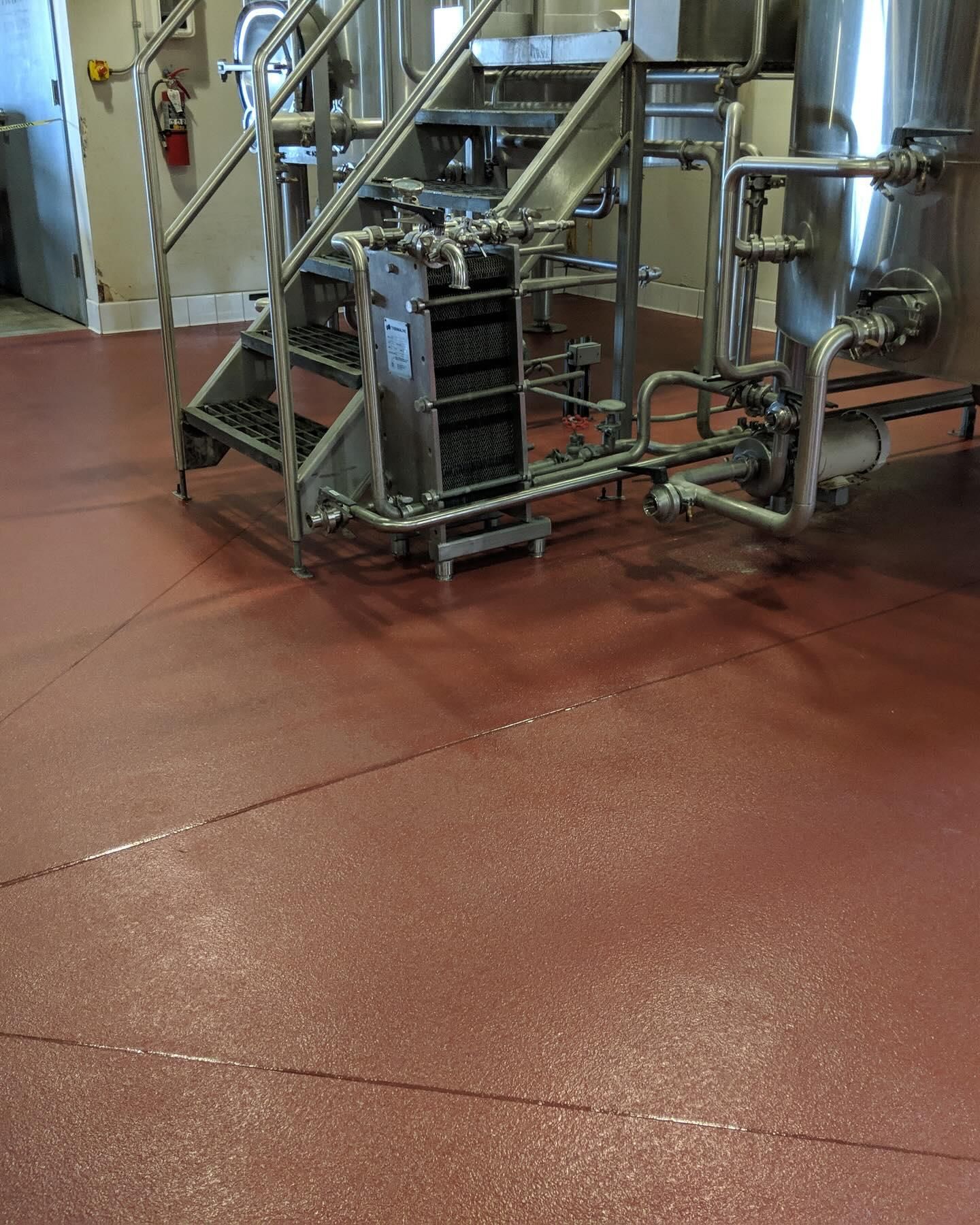 Red industrial flooring with stainless steel equipment in a facility.