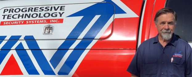 Man standing next to a company van with logo: Progressive Technology Security Systems, Inc.