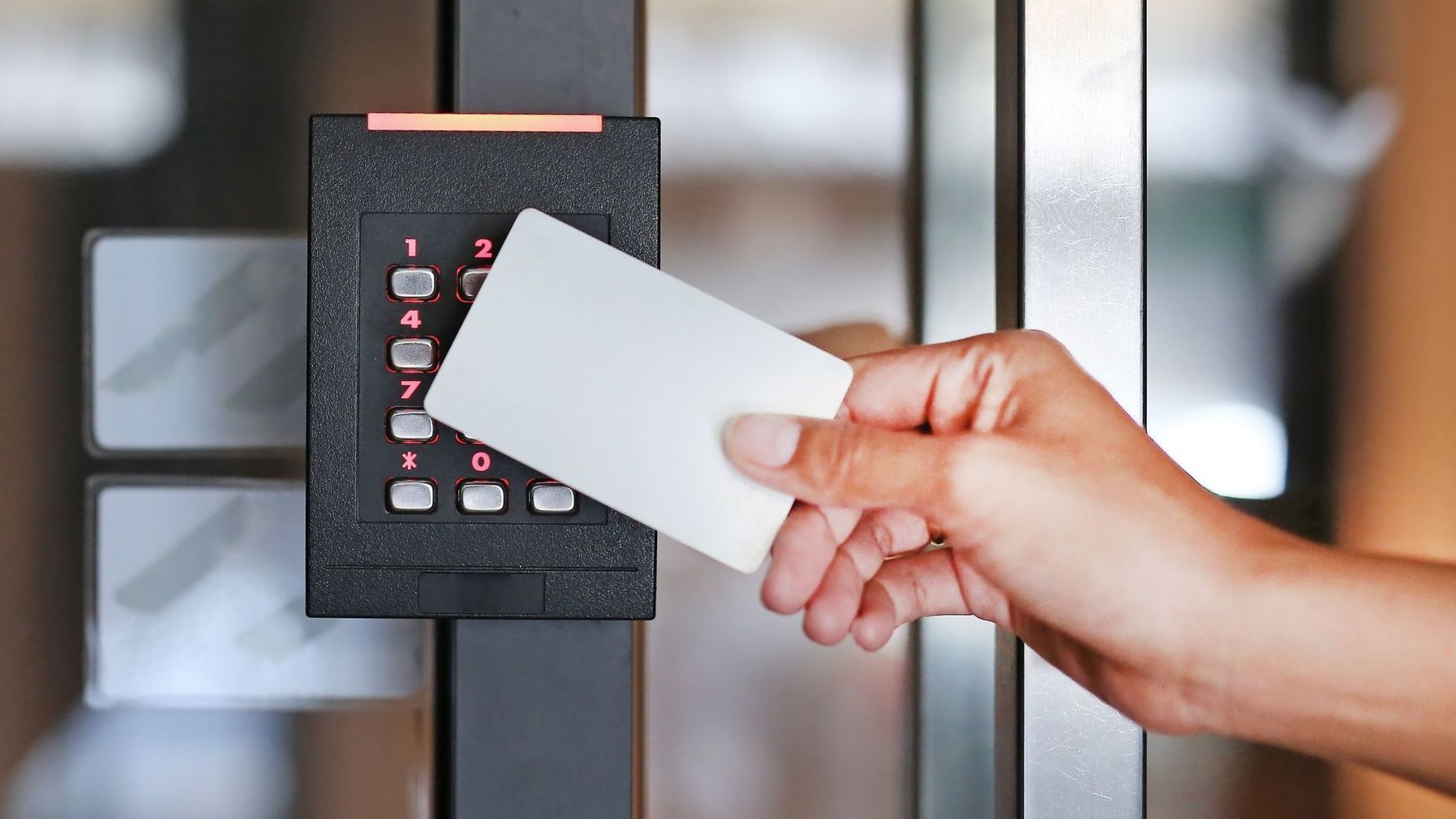 Person using a white access card on a keypad door lock to gain entry.