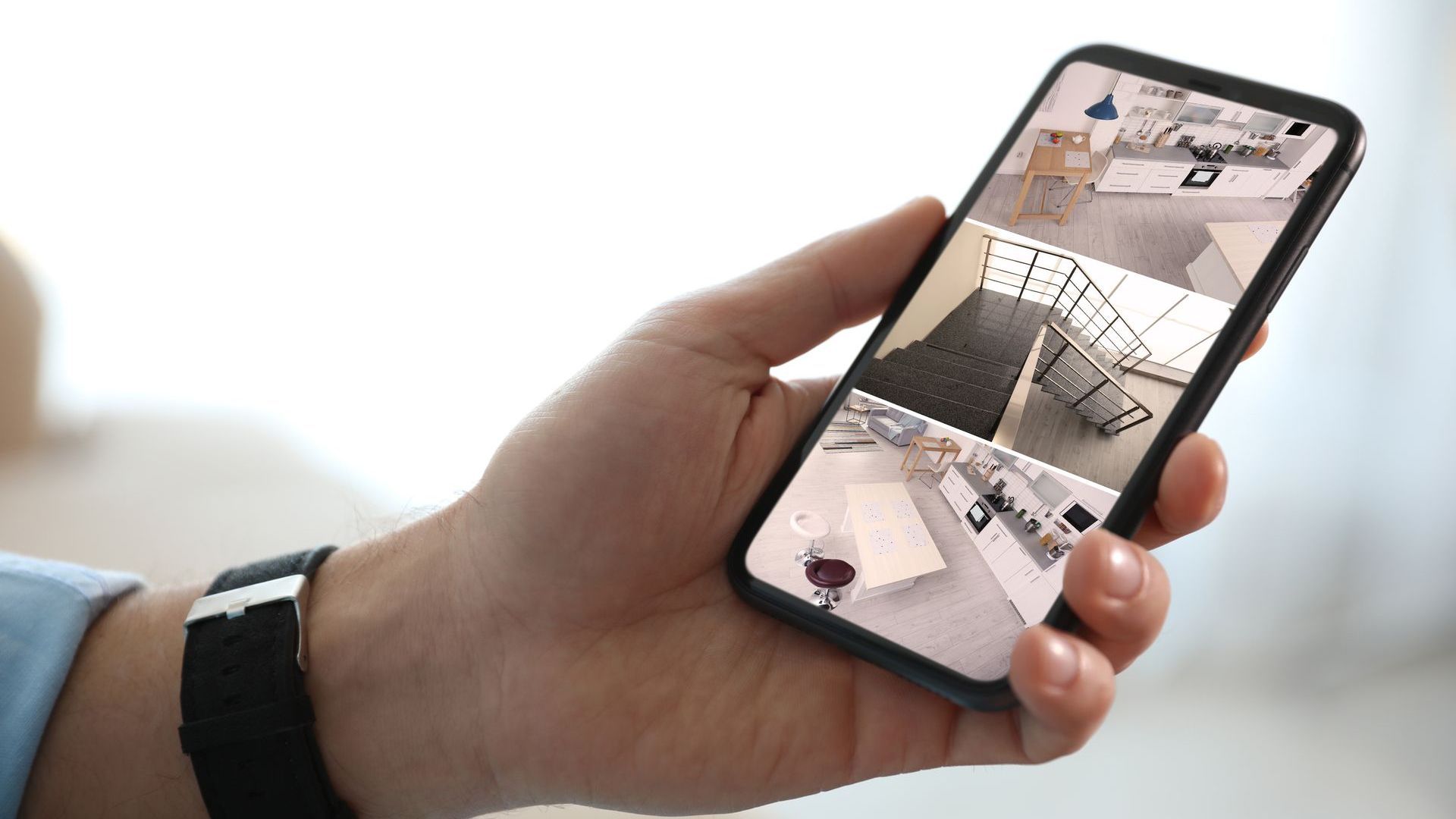 Hand holding a phone displaying a security camera feed of a home interior.