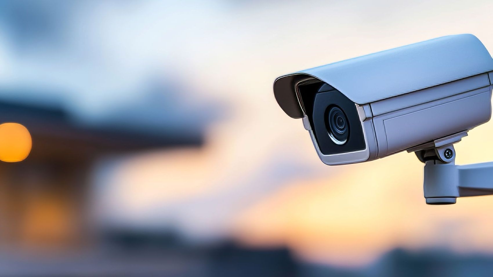 Security camera mounted outdoors, capturing a blurred sunset view.