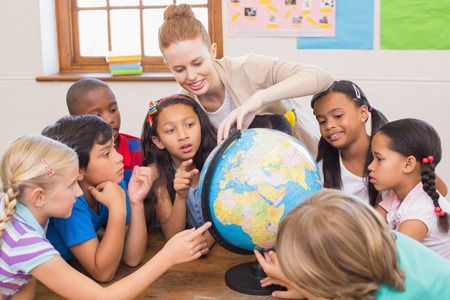 Teacher showing students the globe in a classroom; children point and show surprise.