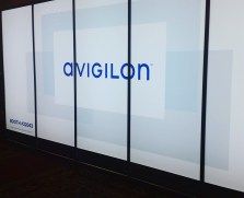 Avigilon logo displayed on a series of connected screens, with a light blue and white geometric background.
