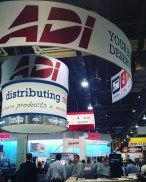 ADI trade show booth with red and white logo; people in a convention hall.
