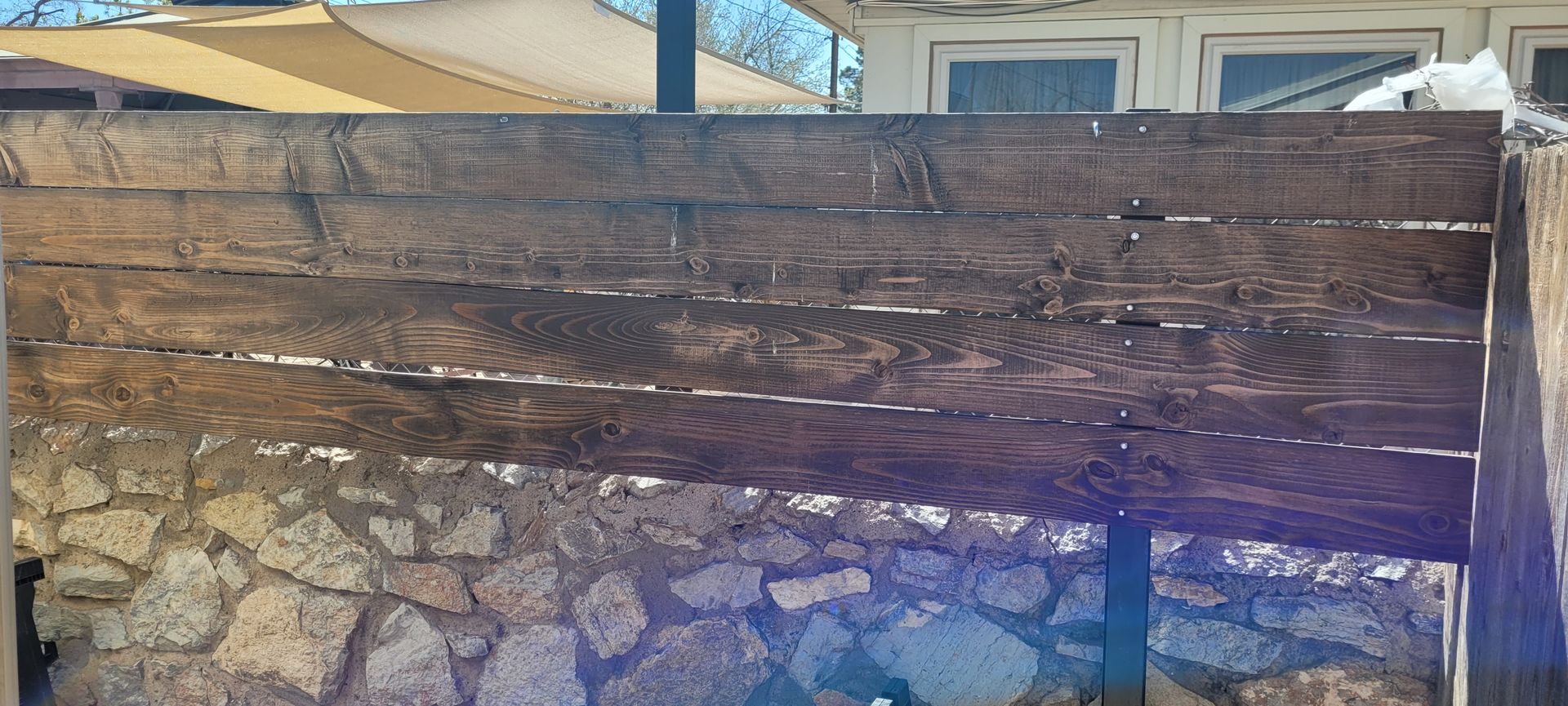 Weathered wooden fence over a stone wall; light from above.