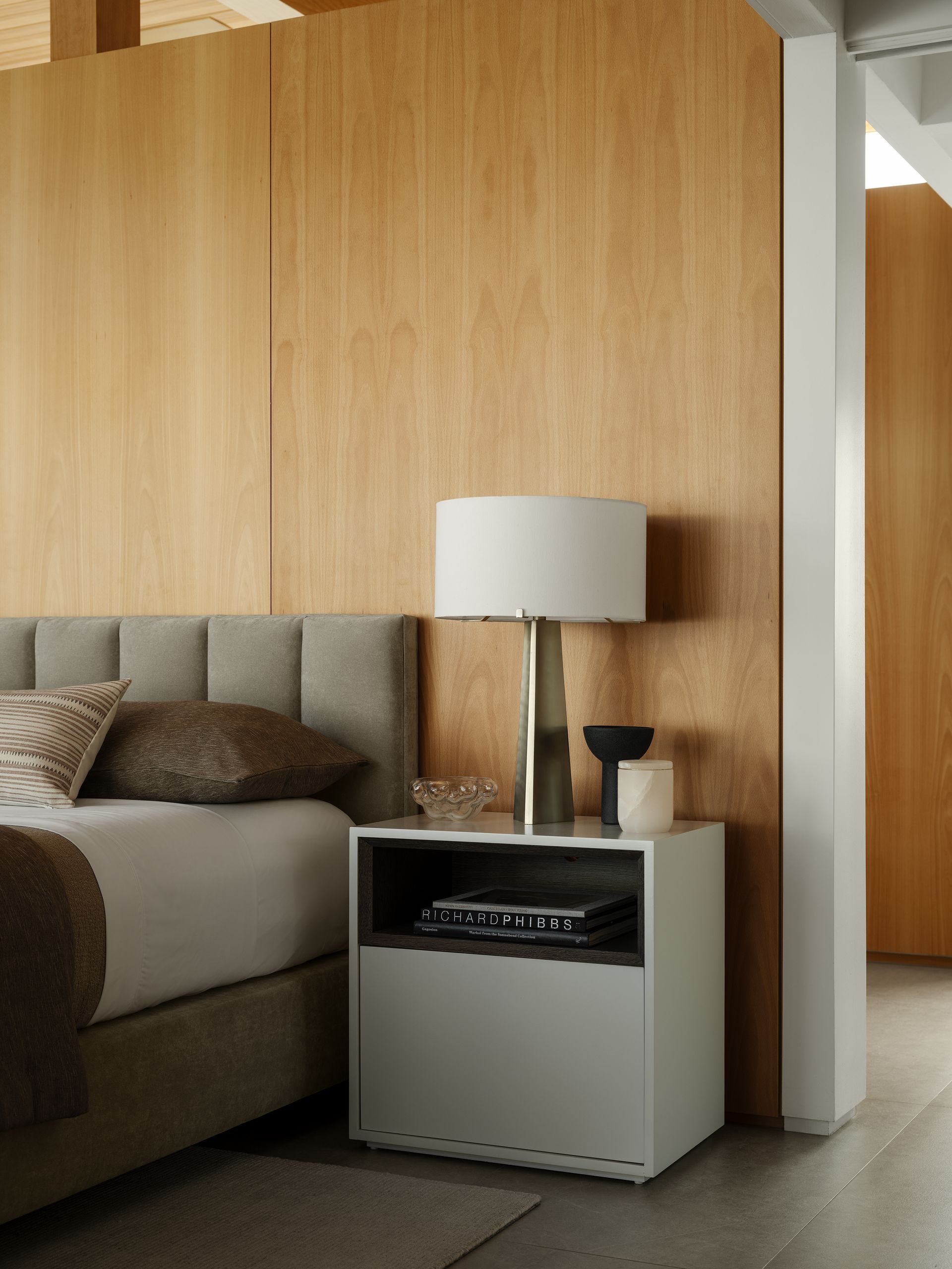 a bedroom with a bed a nightstand and a lamp