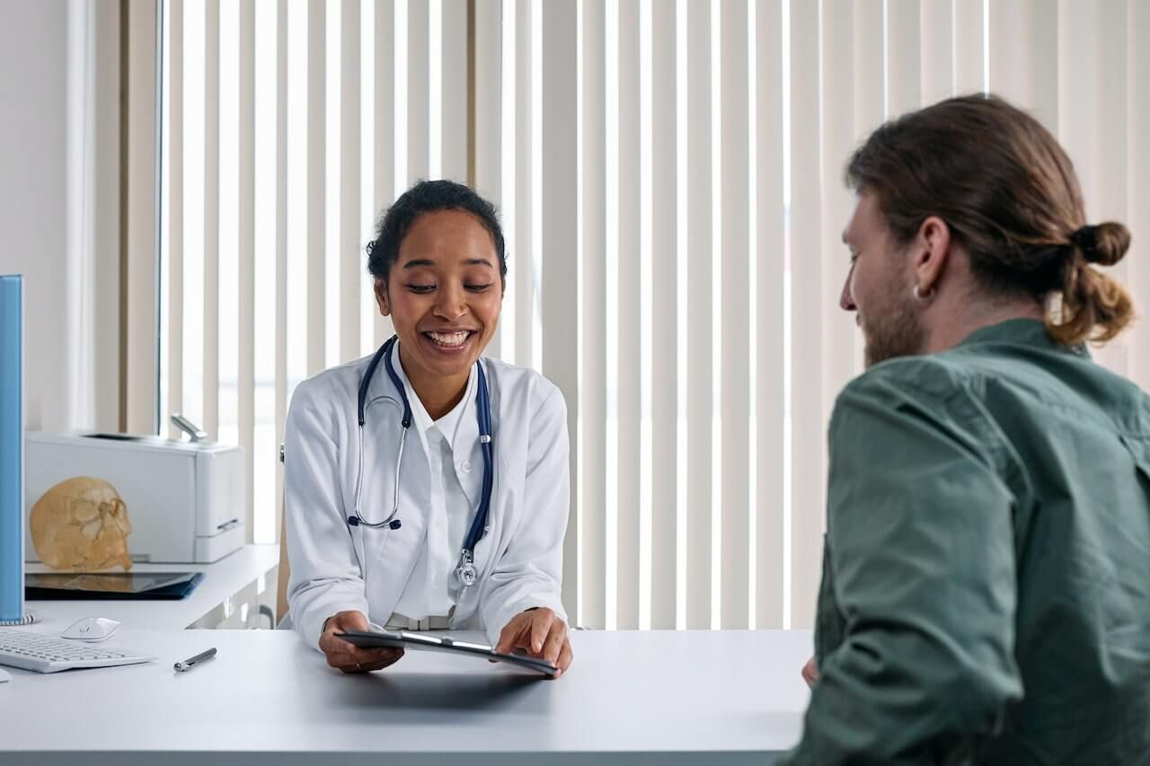 Doctor smiles, reviews chart with patient in office.