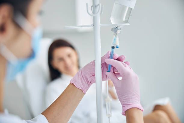 Nurse adjusting IV drip for a patient in a hospital room.