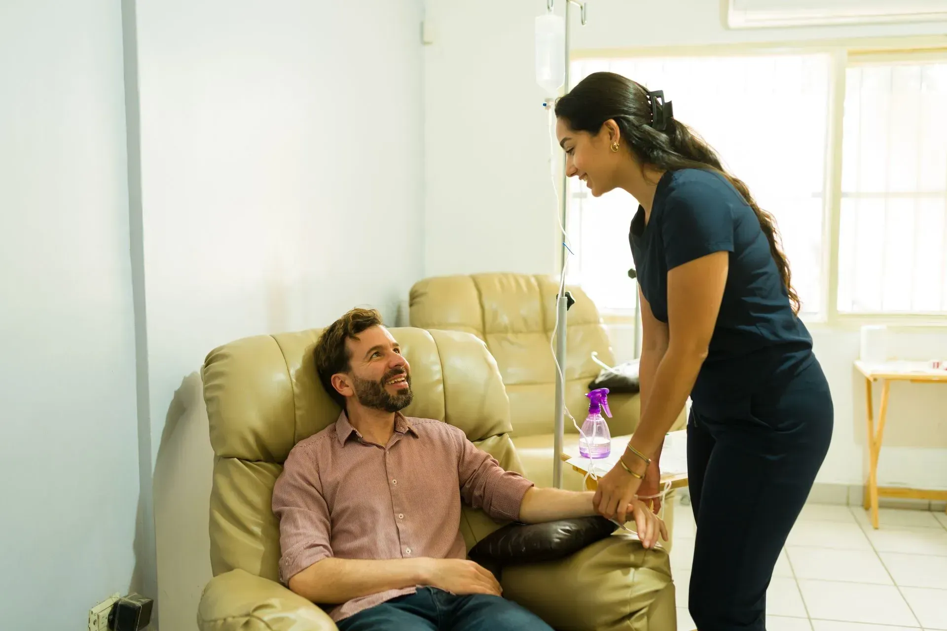 Nurse prepares IV for patient in recliner chair.