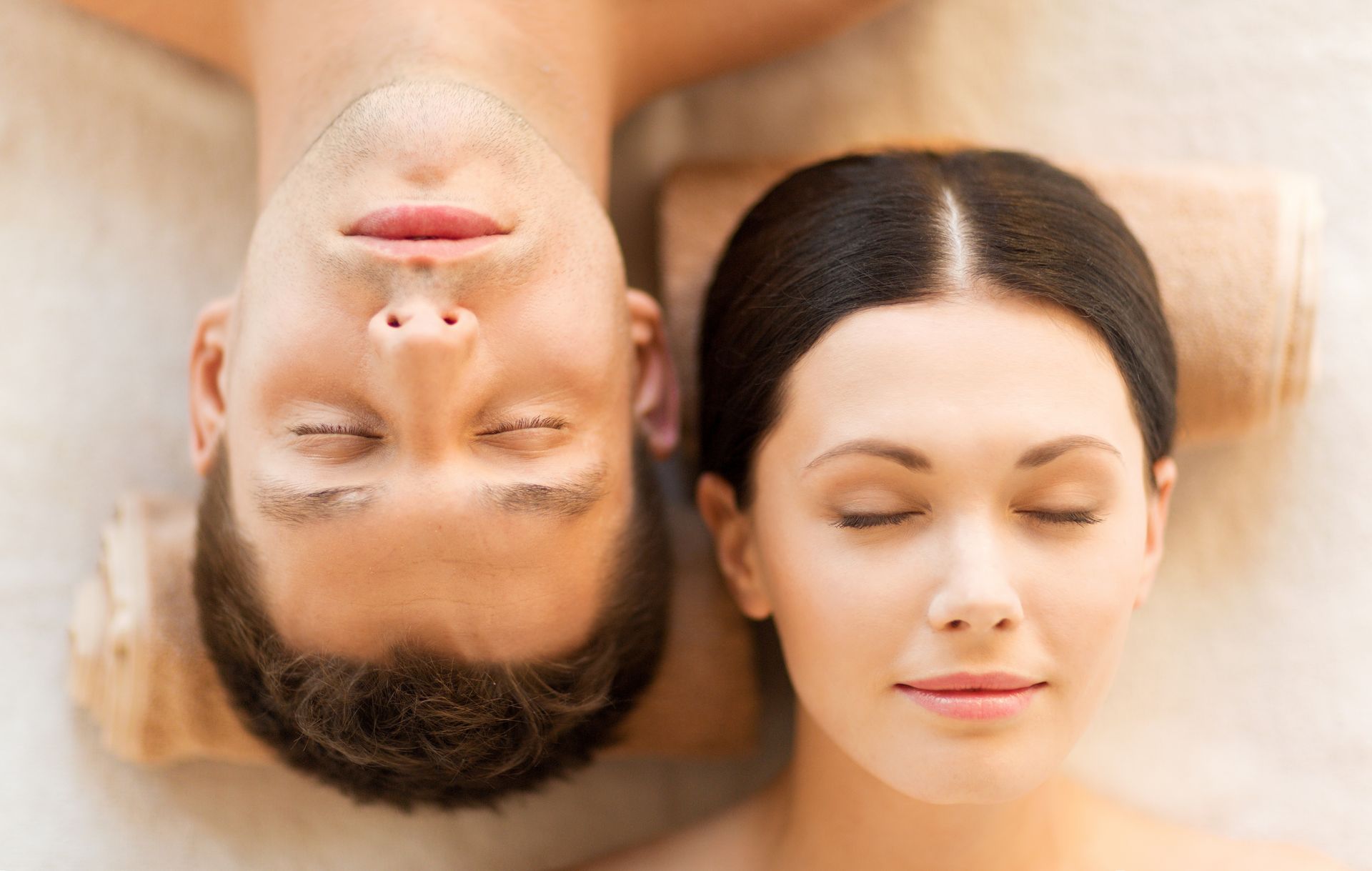 Couple lying down with eyes closed, relaxed, in a spa setting.