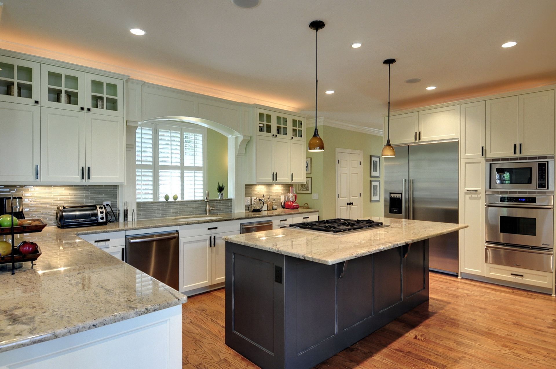 Spacious kitchen with granite counters, a dark gray island, stainless steel appliances, and cream cabinetry.