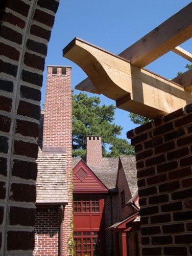 Brick structures, wooden pergola, and chimneys against a blue sky.