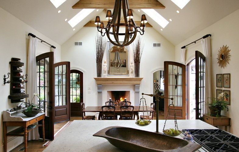 Elegant kitchen with fireplace, chandelier, open doors, and vaulted ceiling; neutral colors.