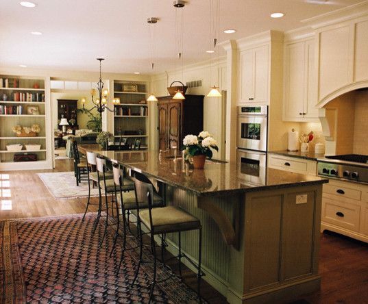 Kitchen with large island, seating, and built-in cabinetry. Warm tones with wood flooring and countertops.