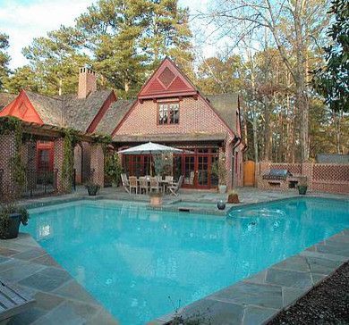 Brick house with a pool in the backyard. A table and chairs sit under an umbrella.