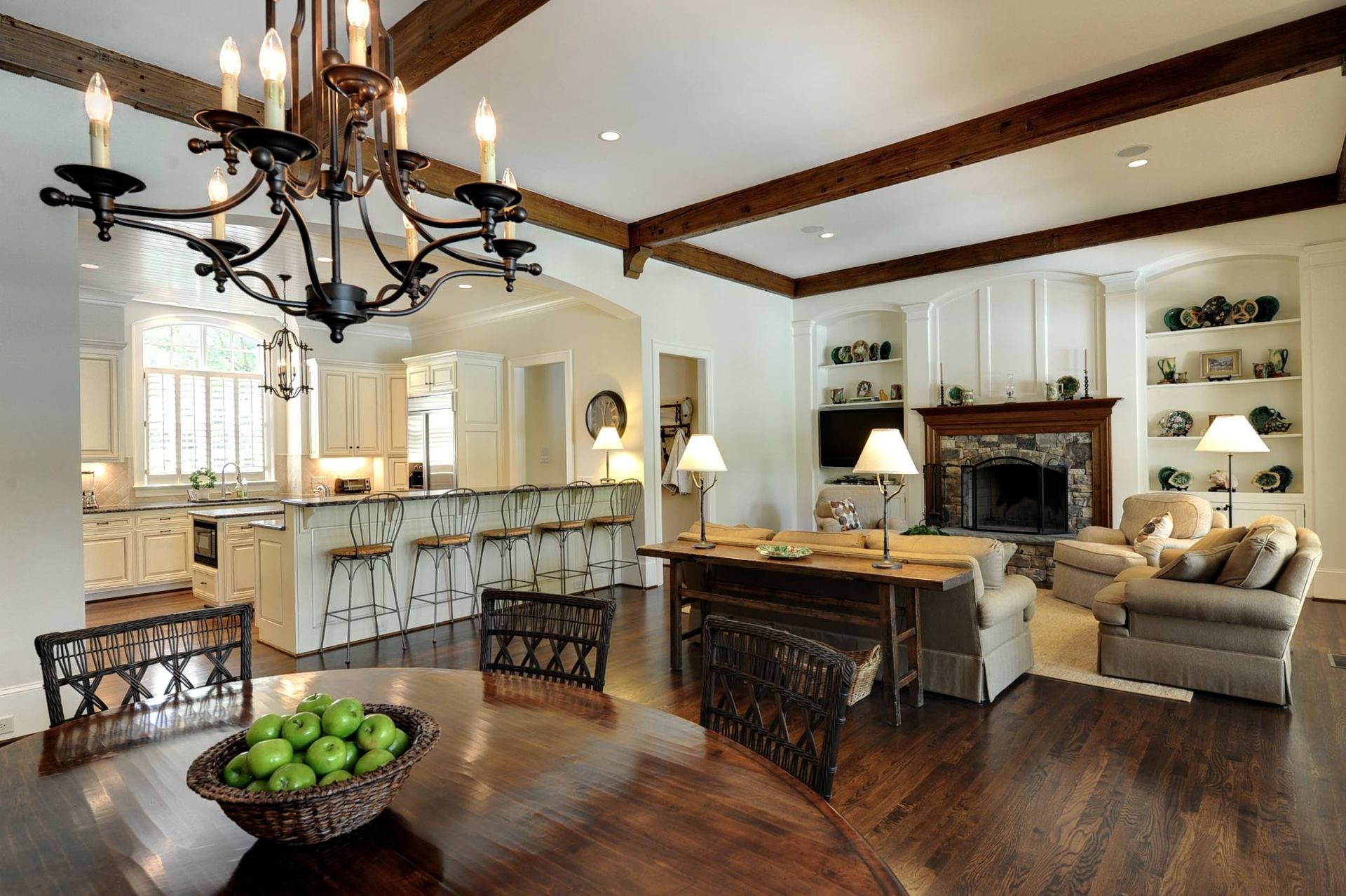 Open-concept living space with kitchen, dining, and living areas. Includes a chandelier, fireplace, and wooden accents.