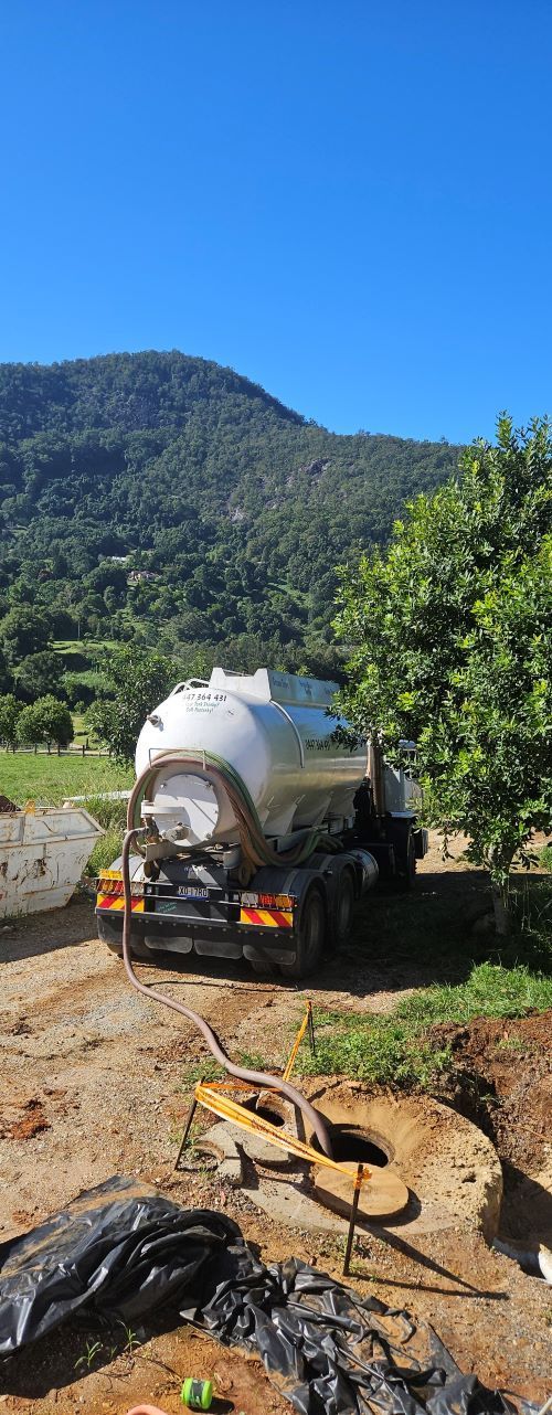 A Tanker Truck is Parked in a Dirt Field With Mountains in the Background — Pootanky Nimbin, NSW