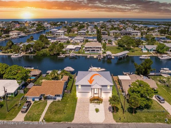 Aerial view of waterfront homes and canals with sunset.