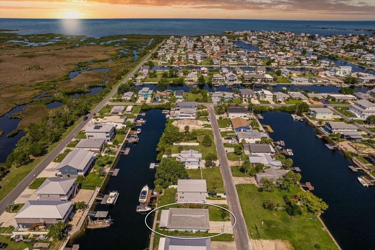 Aerial view of waterfront houses along canals; sunset over the water.