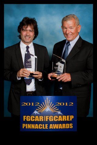 Two men in suits hold awards in front of a blue background at the 2012 FGCAR/FGCAREP Pinnacle Awards.