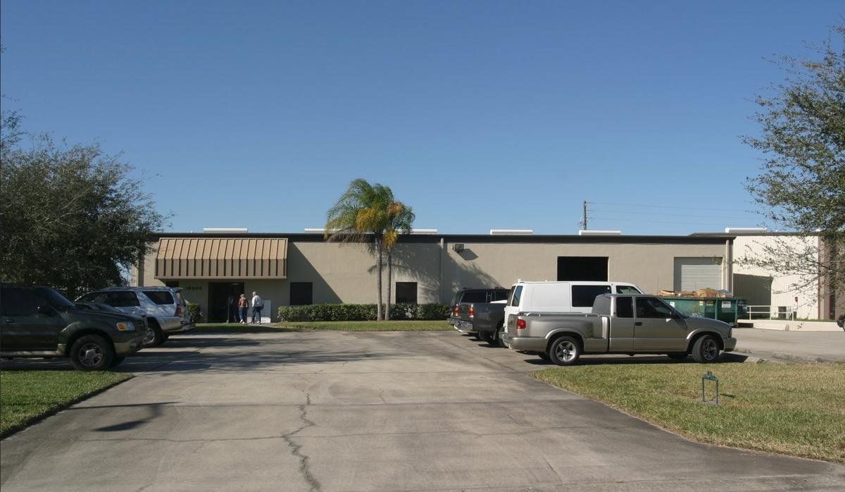 Low industrial building with parked trucks and cars in a sunny lot
