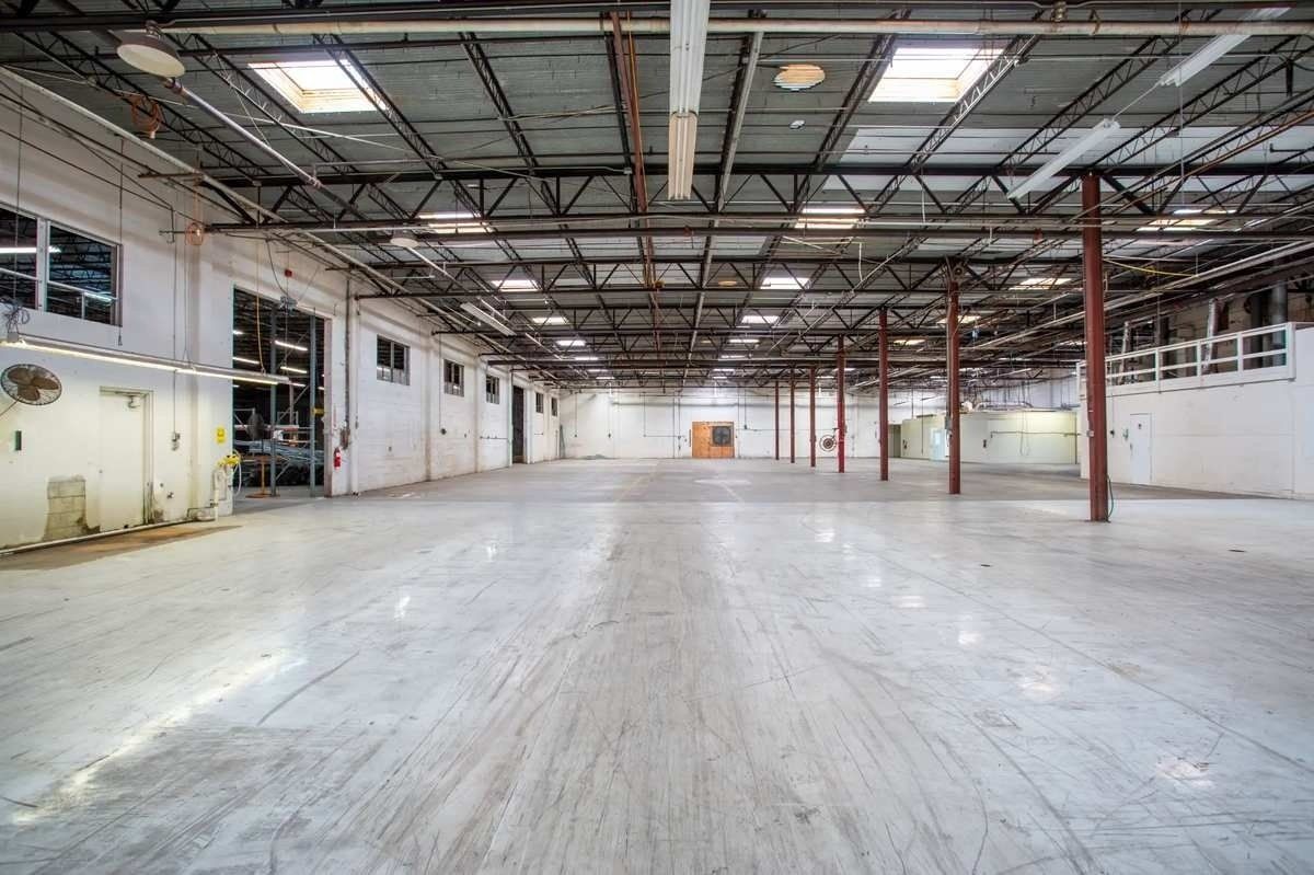 Empty industrial warehouse with high ceilings, concrete floor, and exposed metal beams