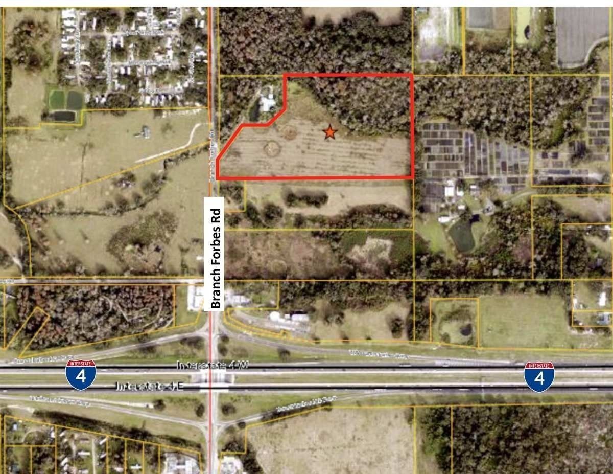 Aerial map with red outlined property near a highway interchange and wooded residential area.