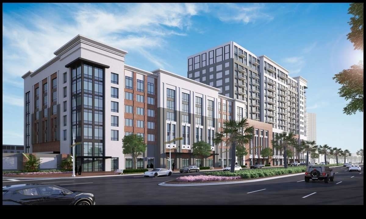 Modern multi-story apartment buildings along a city street under a blue sky.