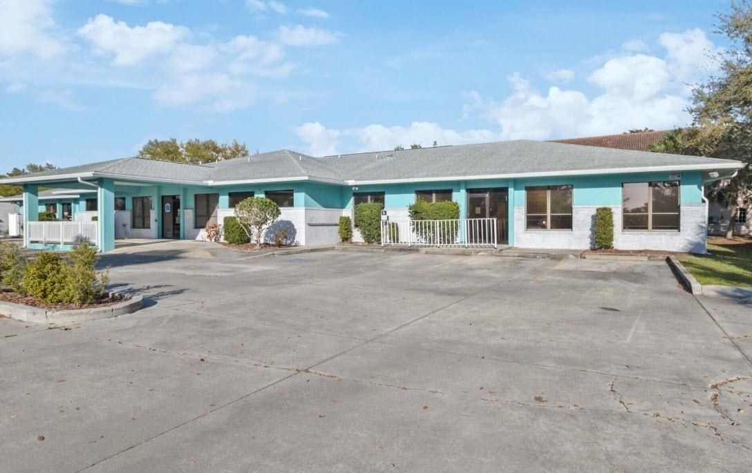 Single-story turquoise house with a large driveway under a blue sky