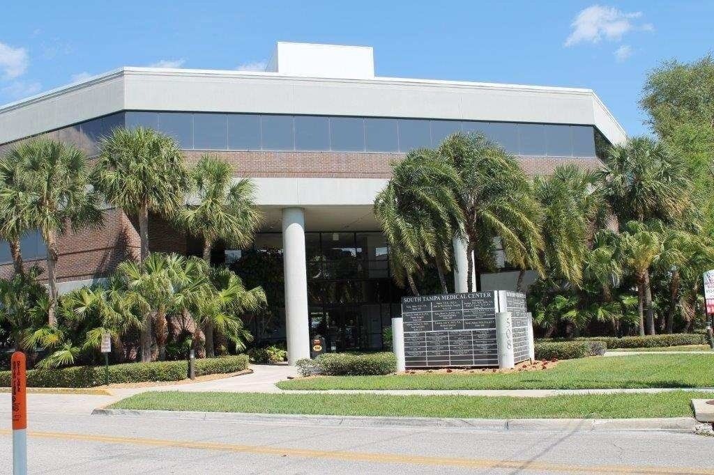 Low-rise building with palm trees and a glass entrance on a sunny day
